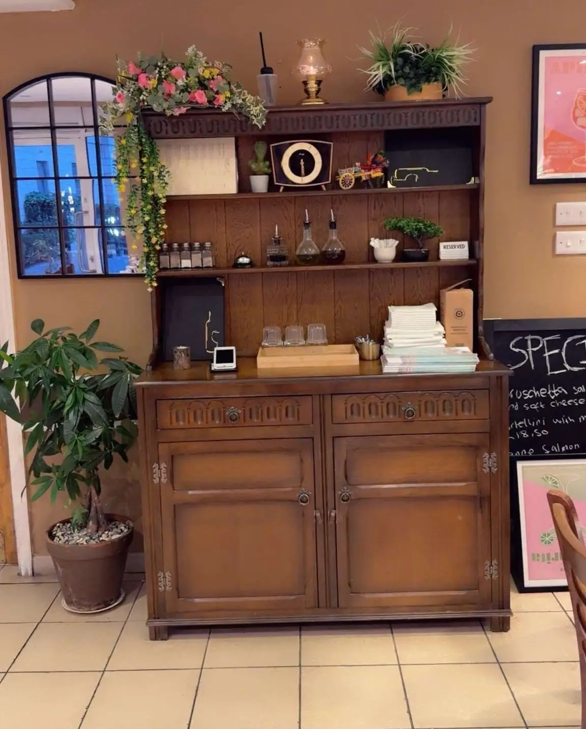 Carved oak dresser with a miniature painted Sicilian cart, flowers and a clock