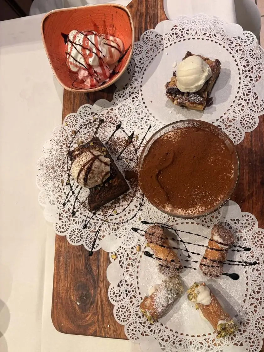 Wooden board with tiramisù, cannoli, brownie, pudding and ice cream