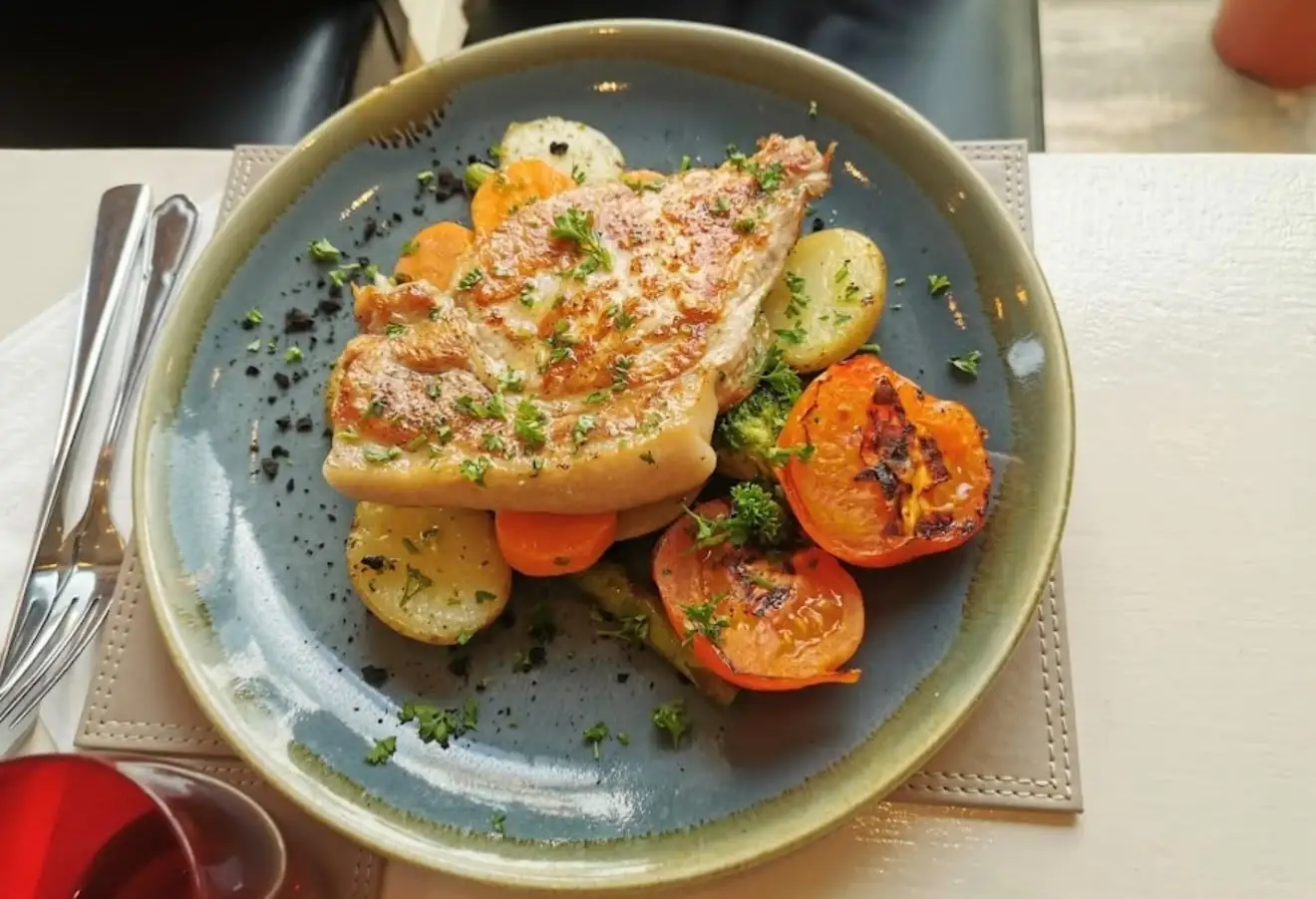 Grilled chicken on potatoes, carrots and broccoli on a blue-green plate