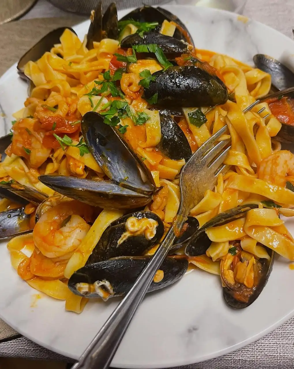 Fork twirling tagliatelle with mussels and prawns in tomato sauce