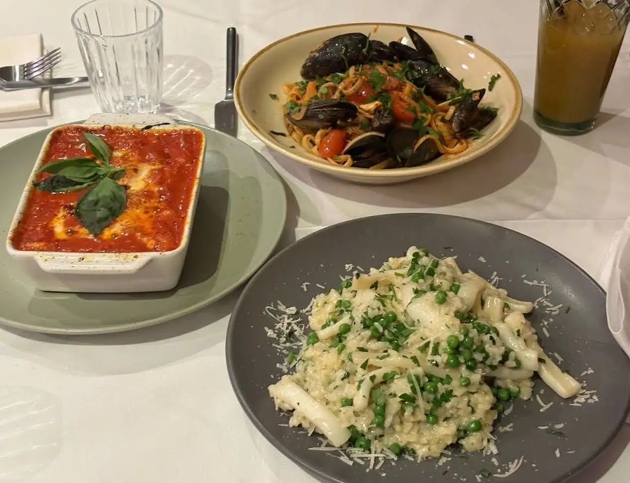 Table with aubergine parmigiana, linguine with mussels and a squid risotto